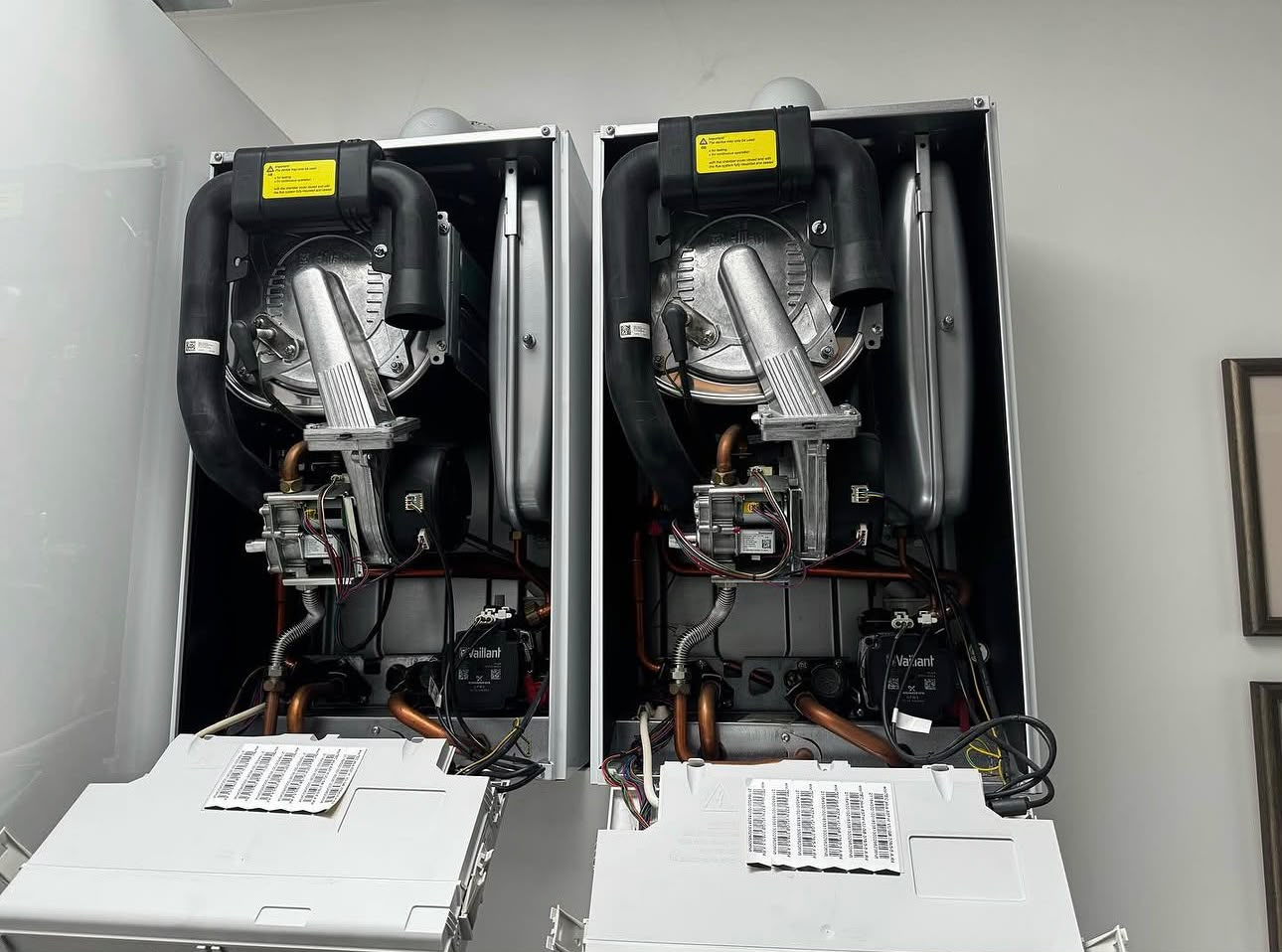 Twin commercial boiler setup with both front panels removed for servicing and commissioning