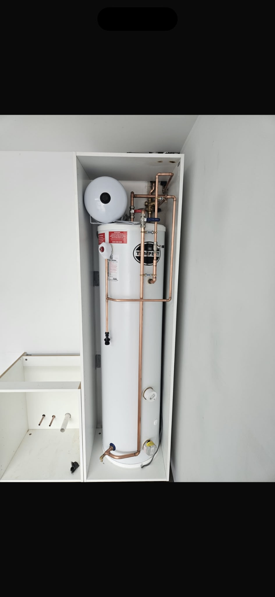 Tall unvented hot water cylinder installation fitted neatly into bespoke white cabinetry with copper pipework