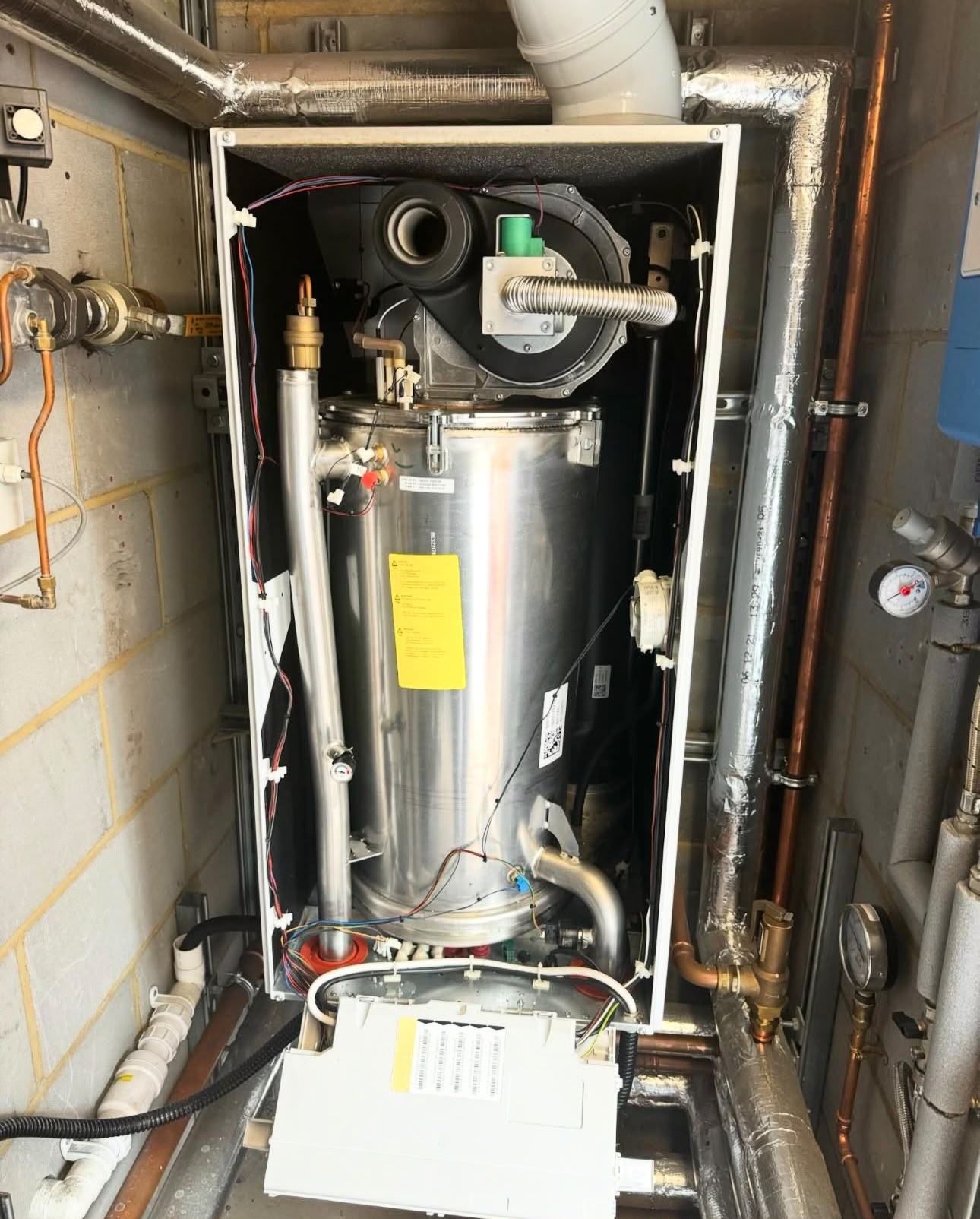 Commercial boiler internals during installation with exposed heat exchanger and neatly routed pipework